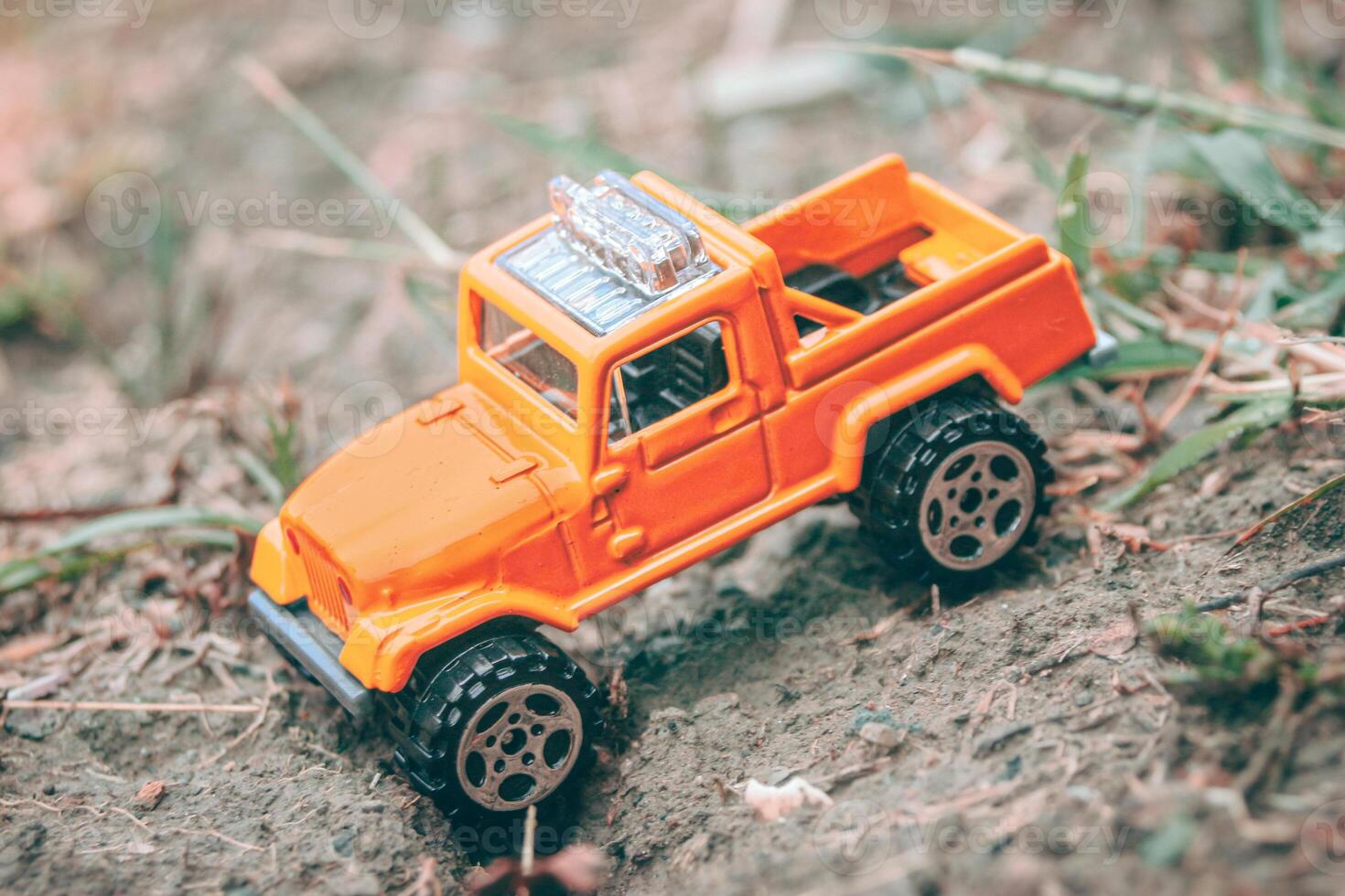 Horizontal photo of miniature 4x4 pickup truck stuck off-road in forest diorama, trying to climb back up. Concept of travel, adventure and overcoming obstacles.