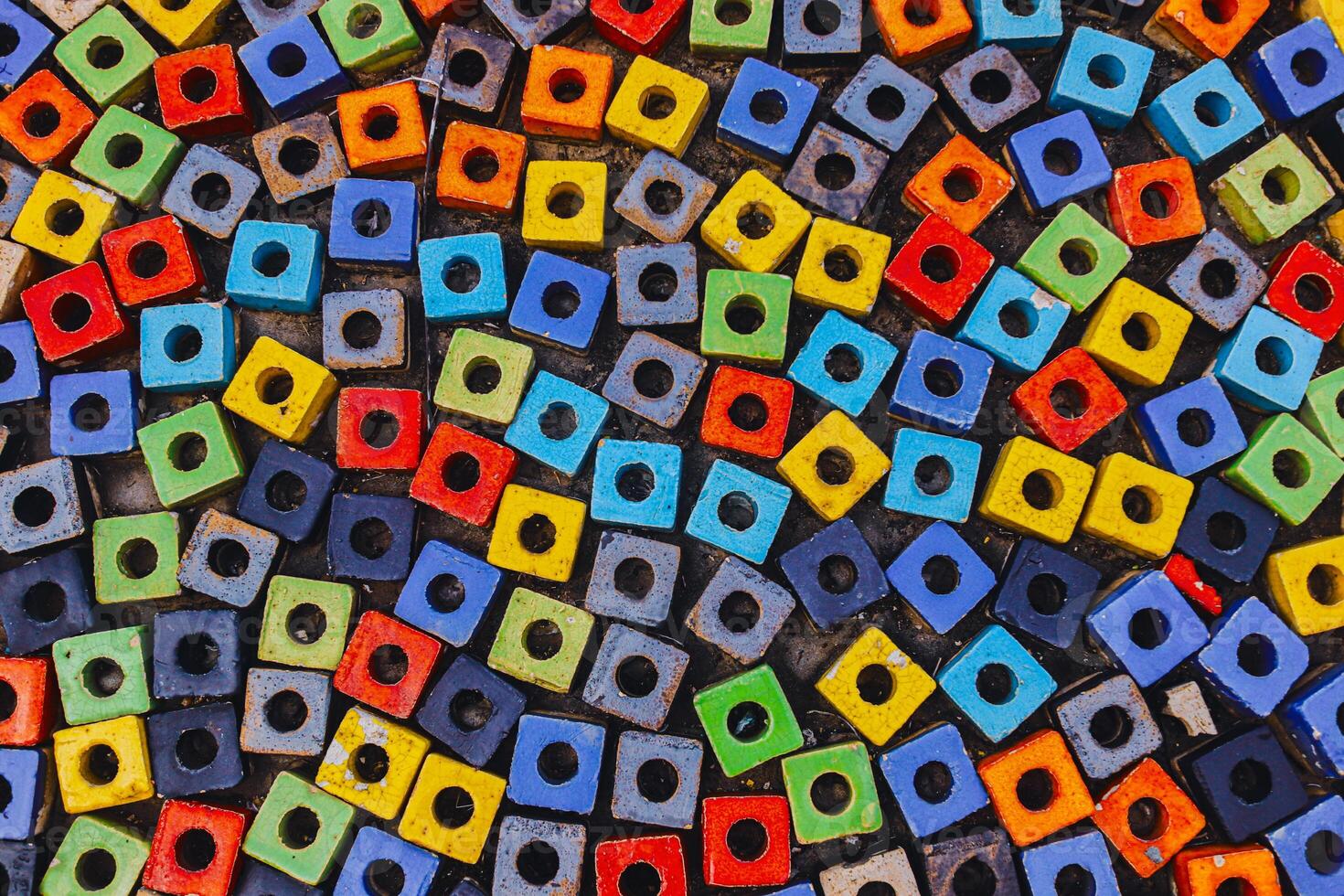 Horizontal close-up of colorful square paving stones with round holes, arranged in alternating directions. Modern abstract pattern background for creative design. photo