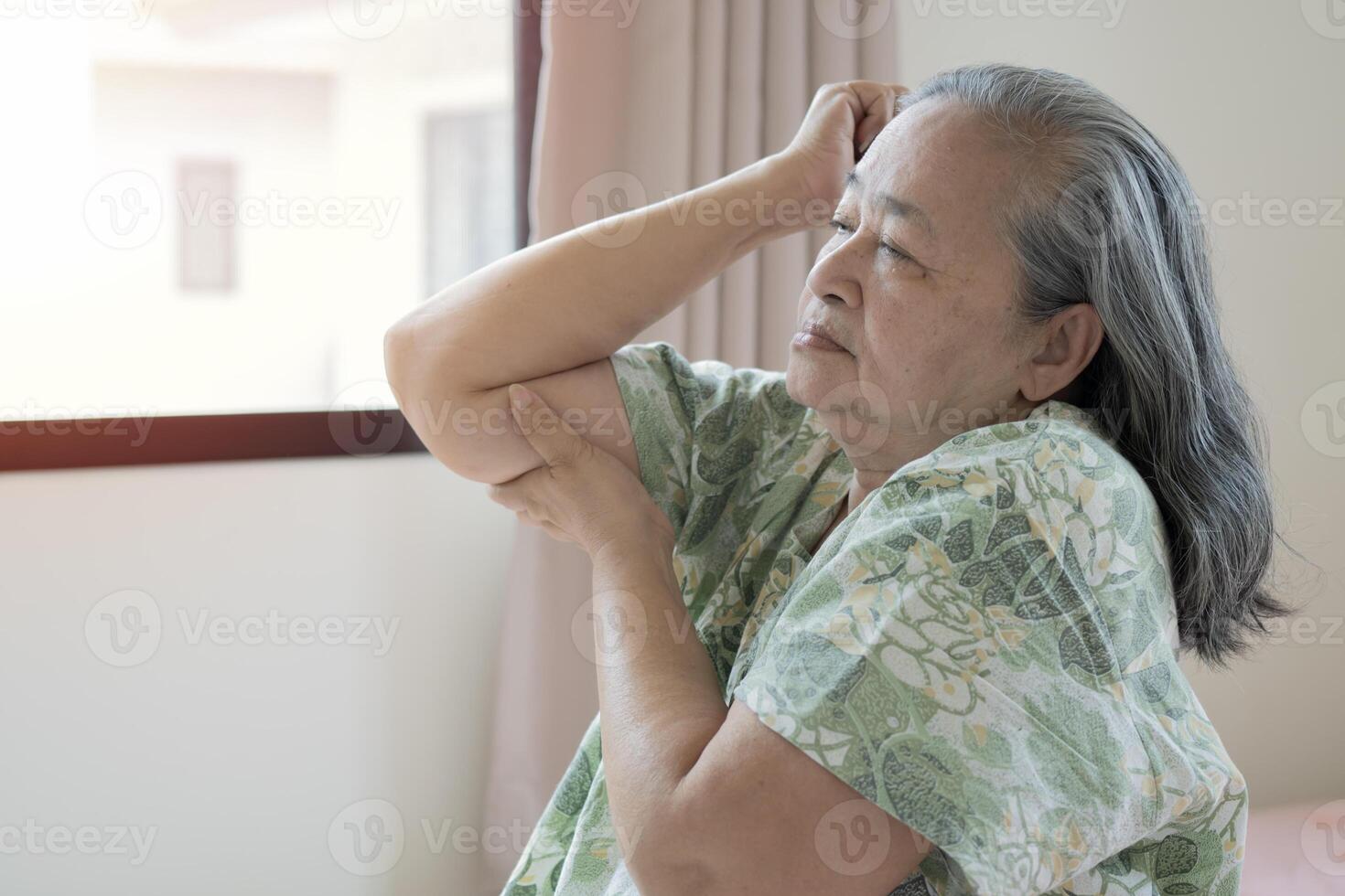 Old Asian woman touching wrist feeling hurt joint pain having osteoarthritis disease. photo