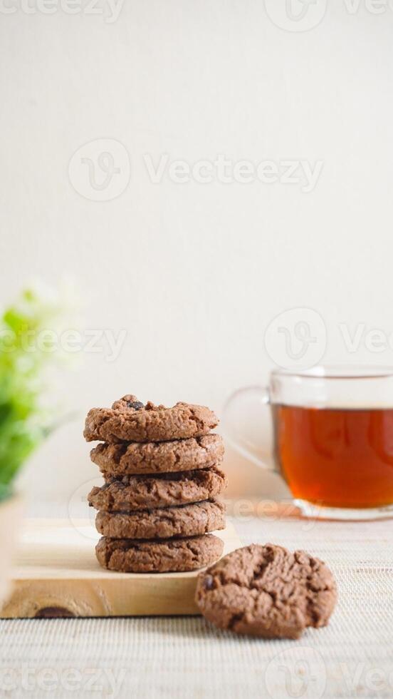 Stack of sweet chocolate cookies on a white plate with a cup of tea isolated on light background photo