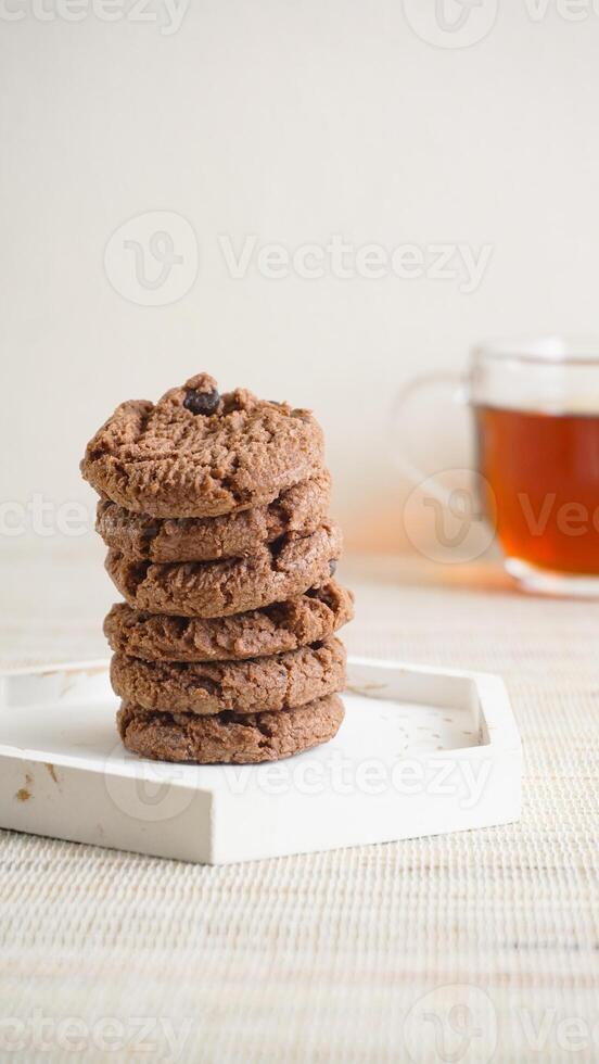 Stack of delicious chocolate cookies on a white plate isolated on light background photo