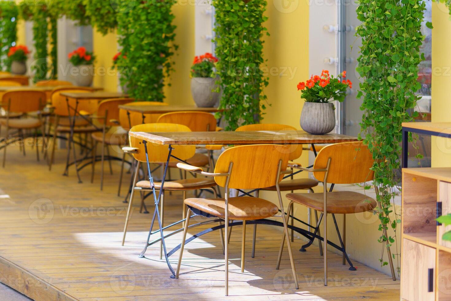 Cozy outdoor cafe with wooden tables and red flowers. Cozy atmosphere of public catering in the restaurant. photo
