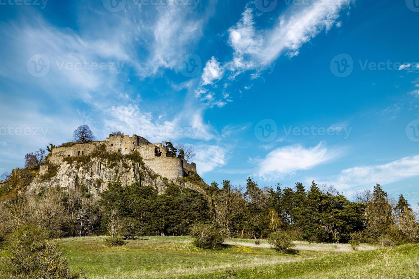 Bottom view of a hill with the ruins of the Hohentwil castle on its top against a blue sky photo