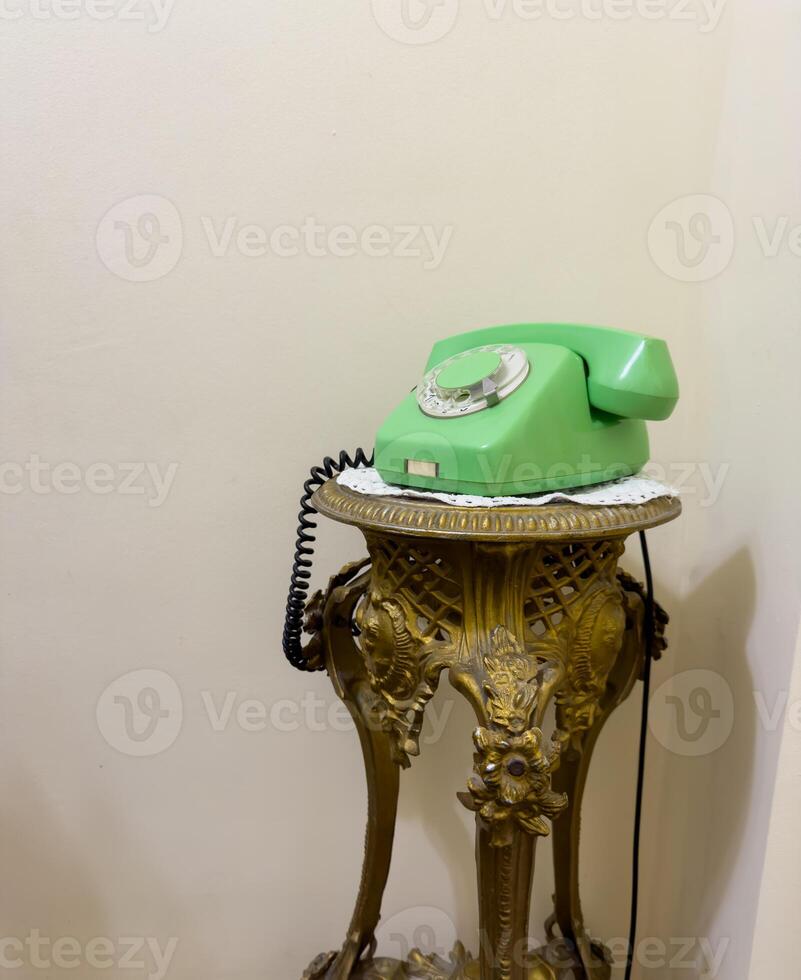 Old green phone is sitting on a gold stand. USSR phone photo