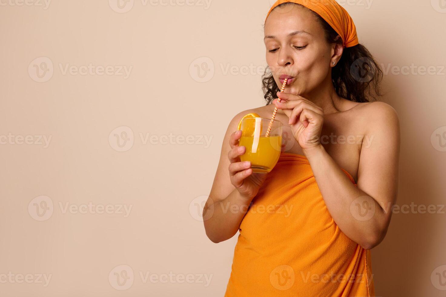 Woman Enjoying Refreshing Orange Juice Against a Neutral Backdrop photo