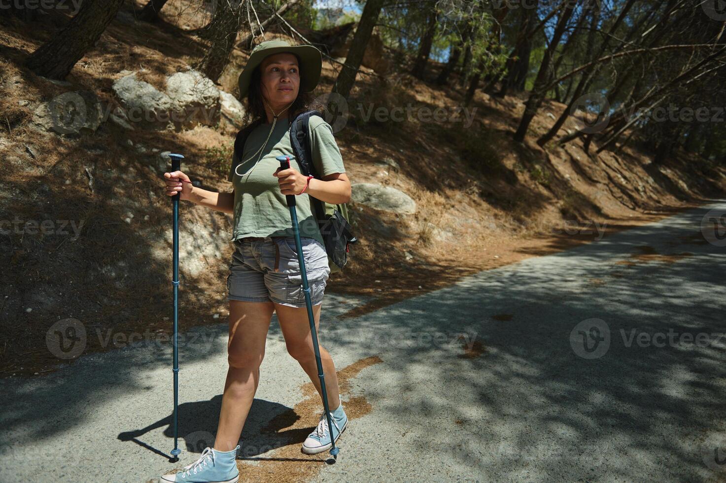 Woman Enjoying a Nature Hike with Walking Poles in a Forested Area on a Sunny Day photo