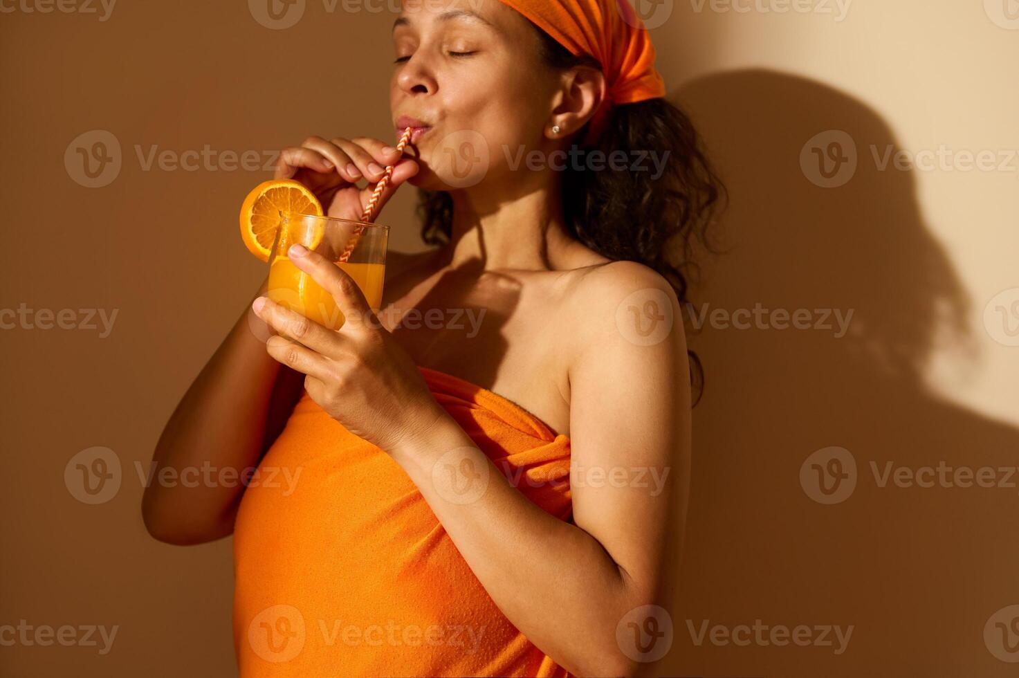 A Relaxed Woman Enjoying Fresh Orange Juice in Warm Toned Setting photo