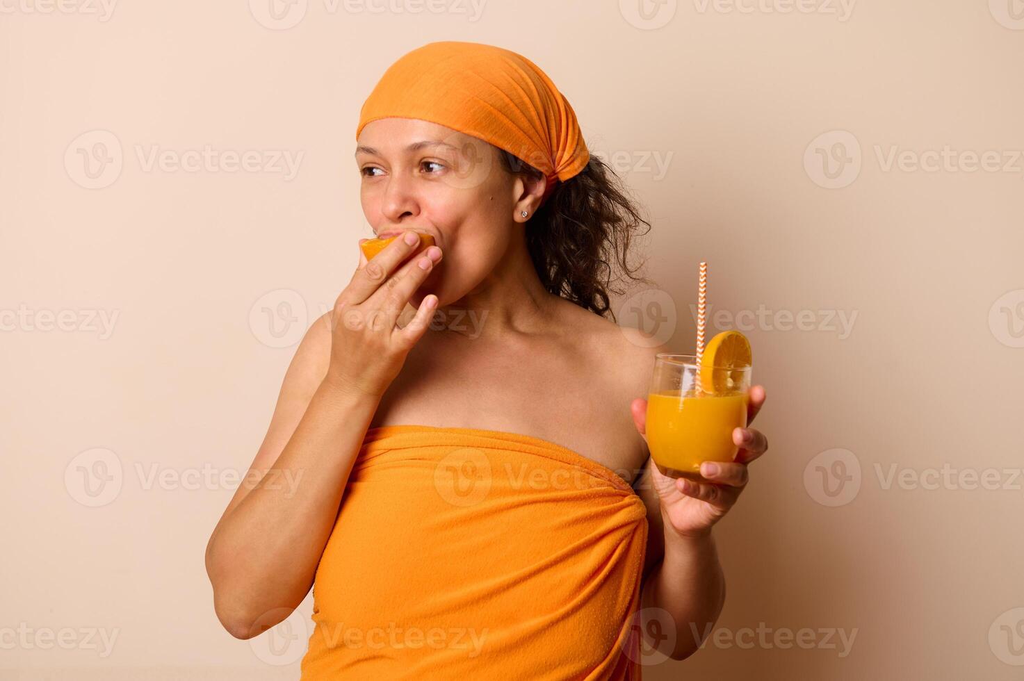 Woman in Orange Clothing Enjoying Fresh Orange Juice with a Slice of Orange photo