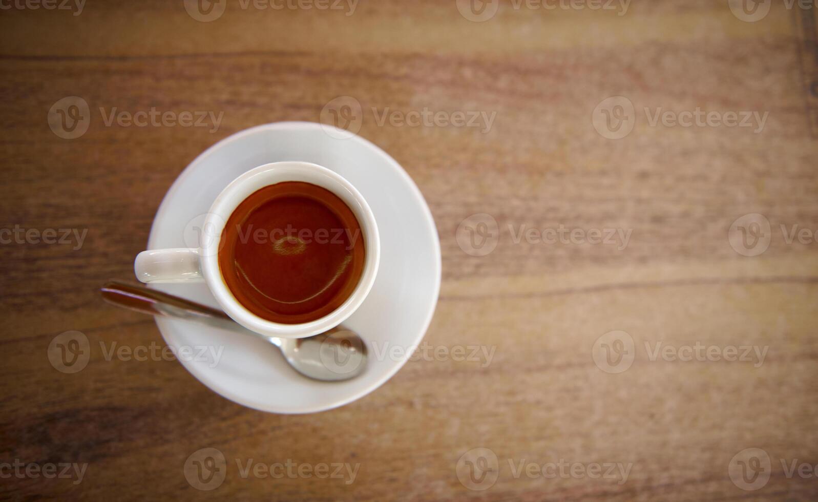 White Cup of Espresso on Wooden Table with a Spoon photo