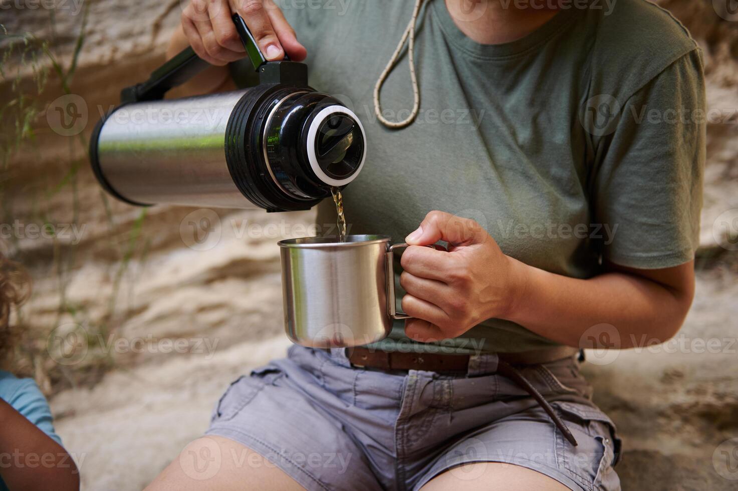 Outdoor Hiker Pouring Beverage from Thermos into Cup During Expedition photo