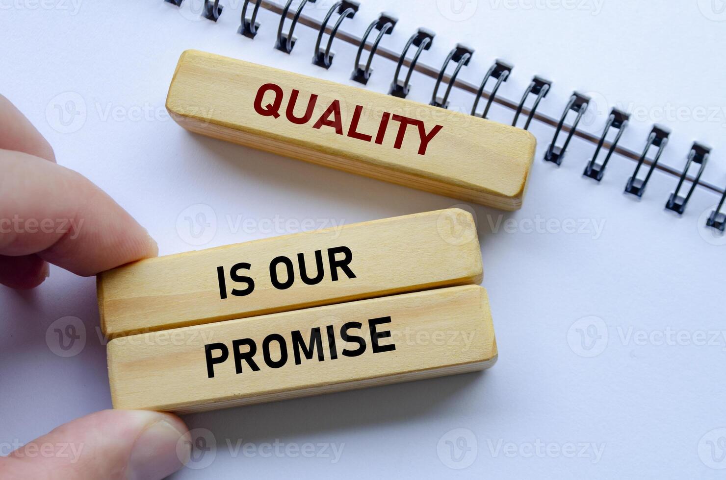 Quality Is Our Promise text on wooden blocks over notebook conveys commitment backed by meaningful intent photo