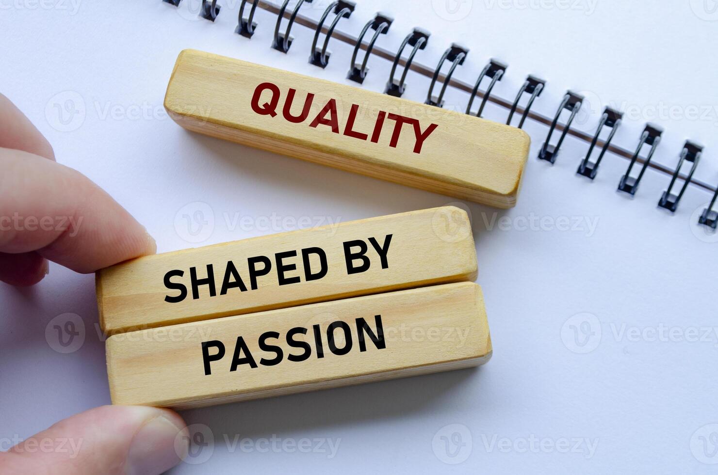 Quality shaped by passion text on wooden blocks over a notepad reflects teamwork driven by genuine enthusiasm photo