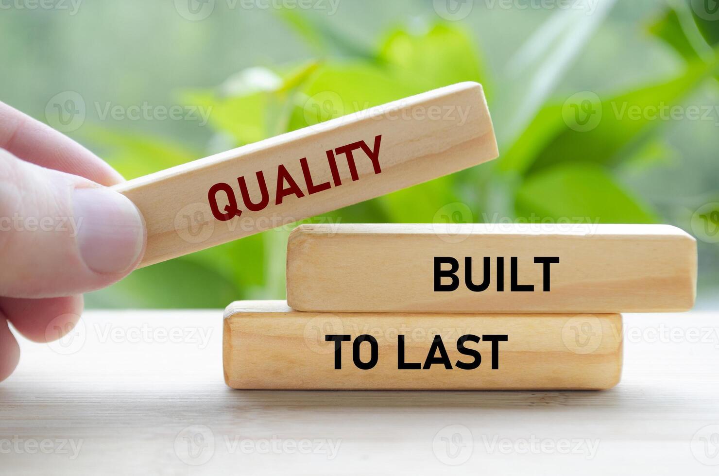 Quality Built to last text on green wooden blocks held by hand represents durability and long-term reliability photo