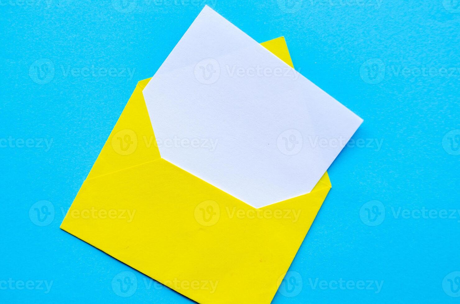 Top view of white notepad with envelope on blue cover background with customizable space for text or ideas.. photo