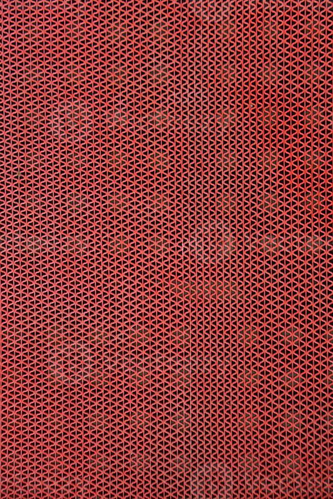 Close-up of a textured red rubber mat with repeating triangle pattern and dark background photo