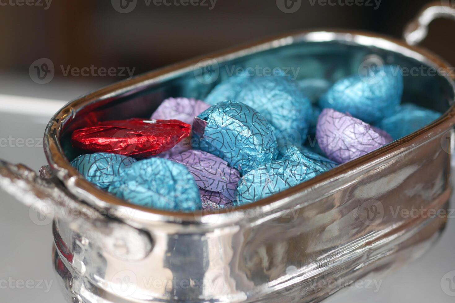 Colorful wrapped candies in a silver dish on a table photo
