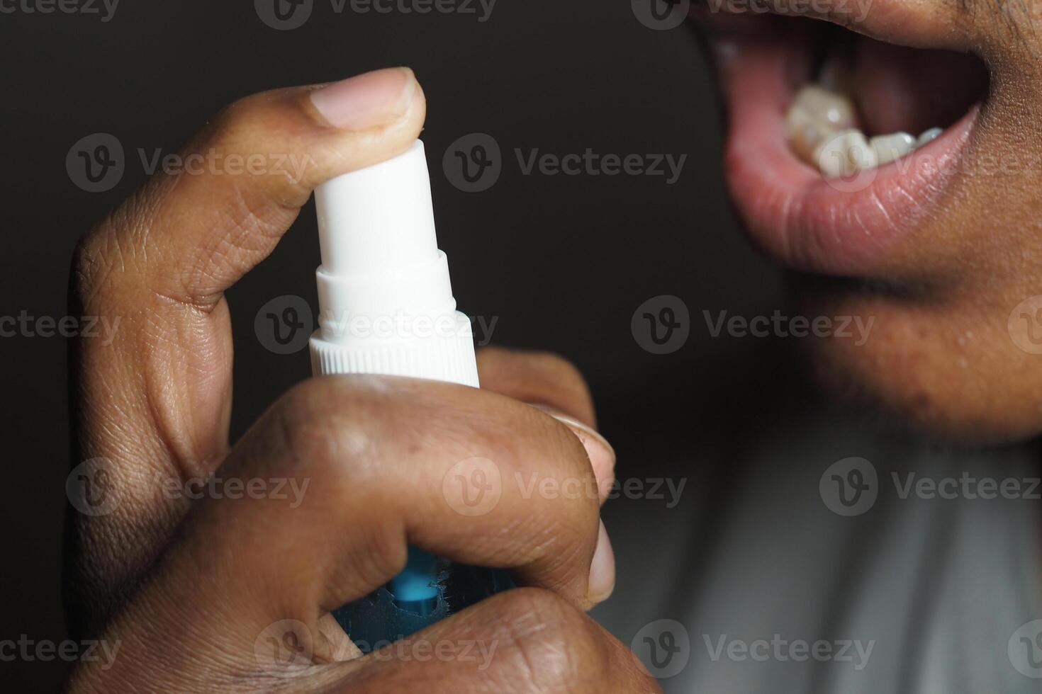Person using mouth spray for fresh breath in close-up shot photo