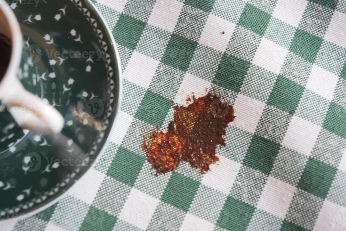 Coffee spill on a green and white checkered tablecloth photo