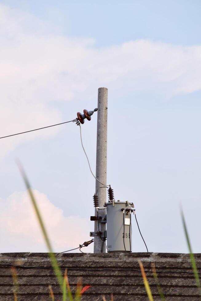 Power pole standing on tiled house roof photo