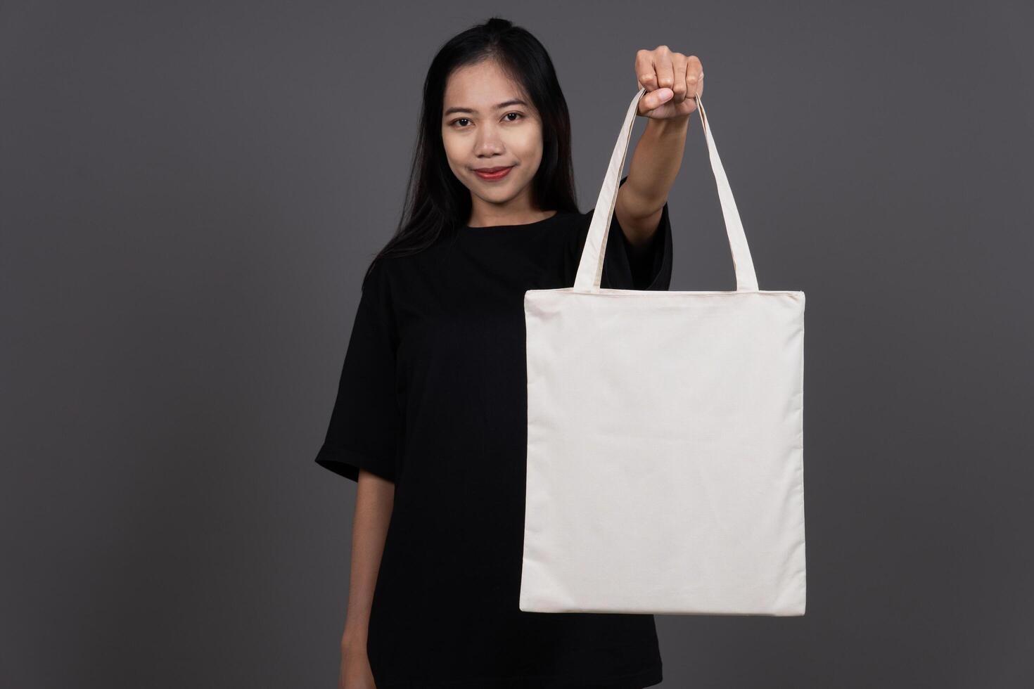 Front View of Woman Holding Blank Canvas Tote Bag, Eco-Friendly Reusable Fabric with Handle, Close-Up Mockup, No Plastic and Environmental Concept And Presenting photo