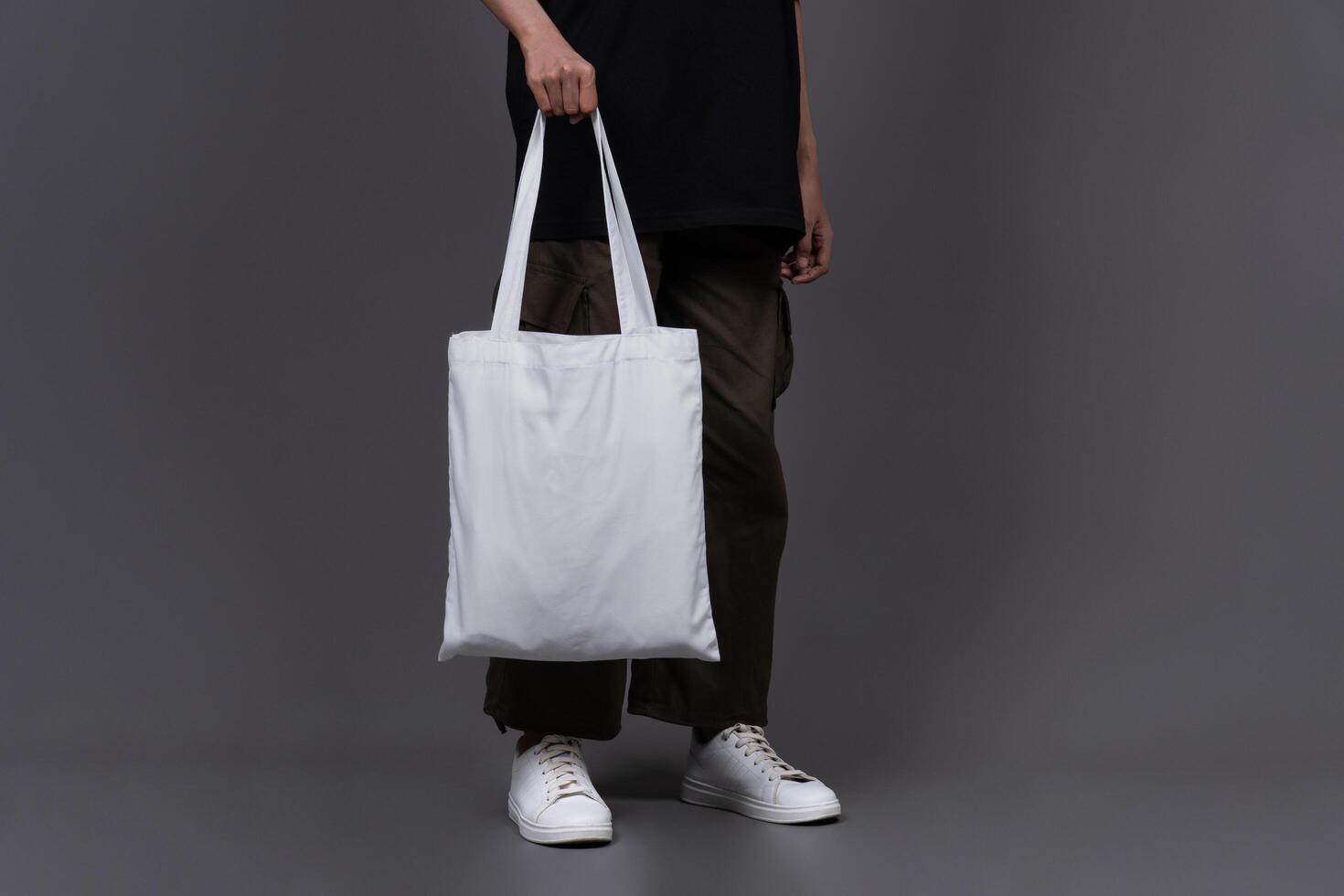 Front View of Woman Holding Blank Canvas Tote Bag, Eco-Friendly Reusable Fabric with Handle, Close-Up Mockup, No Plastic and Environmental Concept Background photo