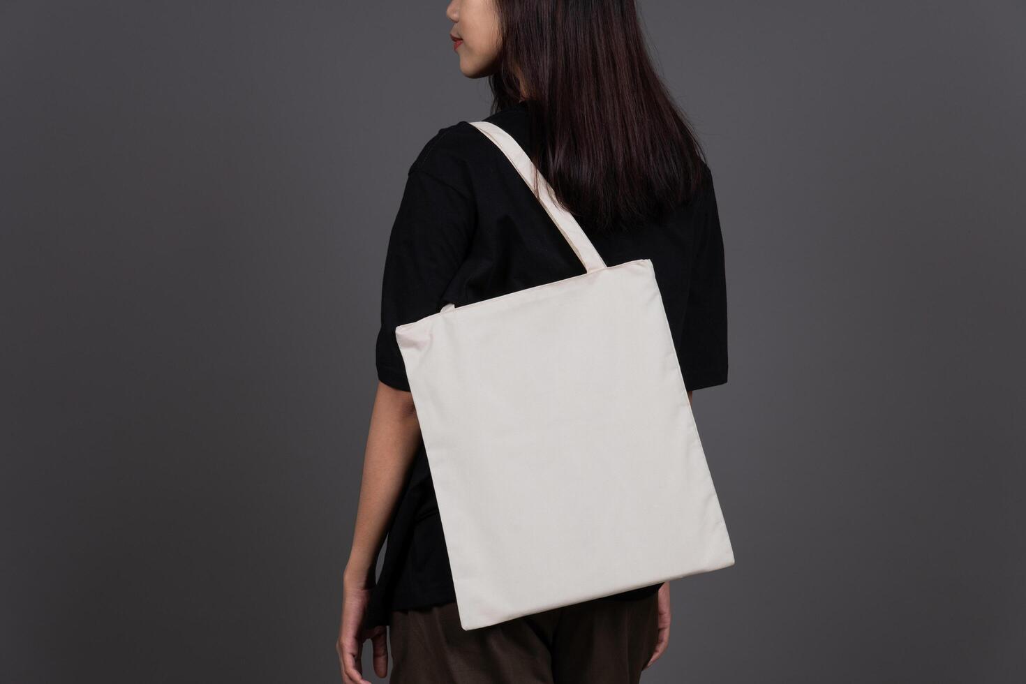 Back View of Female Holding Blank Canvas Tote Bag, Eco-Friendly Reusable Fabric with Handle, Close-Up Mockup, No Plastic and Environmental Concept Background photo