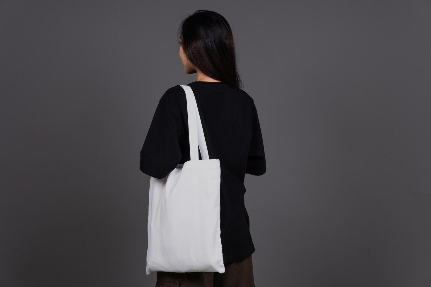 Back View of Female Holding Blank Canvas Tote Bag, Eco-Friendly Reusable Fabric with Handle, Close-Up Mockup, No Plastic and Environmental Concept Isolated Background photo
