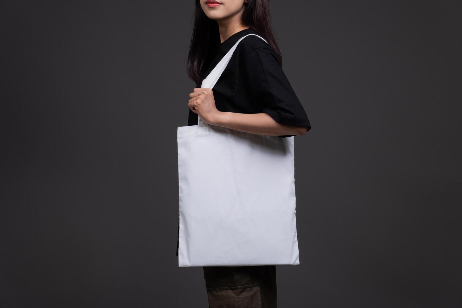Side View of Female Holding Blank Canvas Tote Bag, Eco-Friendly Reusable Fabric with Handle, Close-Up Mockup, No Plastic and Environmental Concept Background photo
