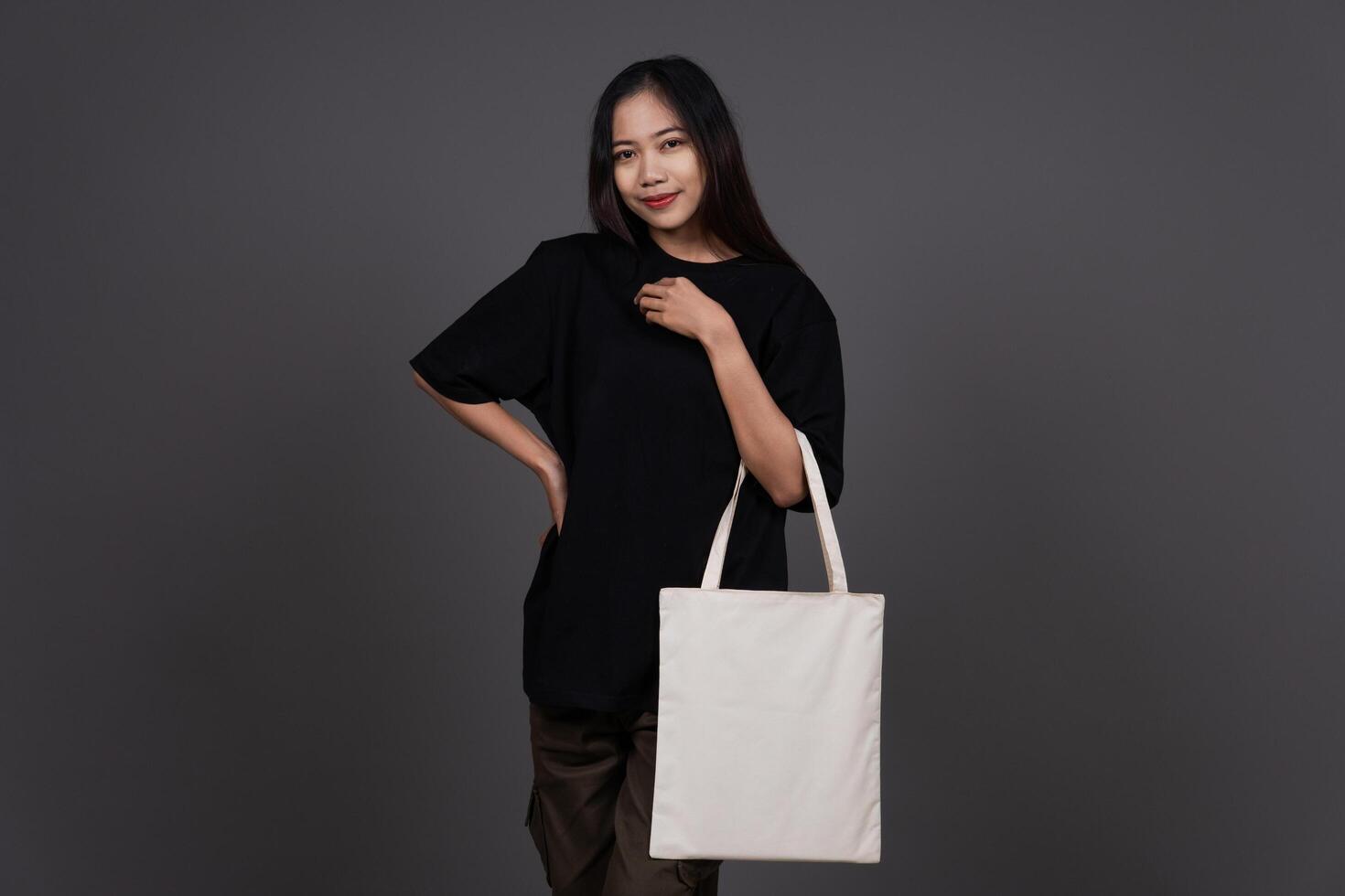 Front View of Beauty Woman Holding Blank Canvas Tote Bag, Eco-Friendly Reusable Fabric with Handle, Close-Up Mockup, No Plastic and Environmental Concept photo