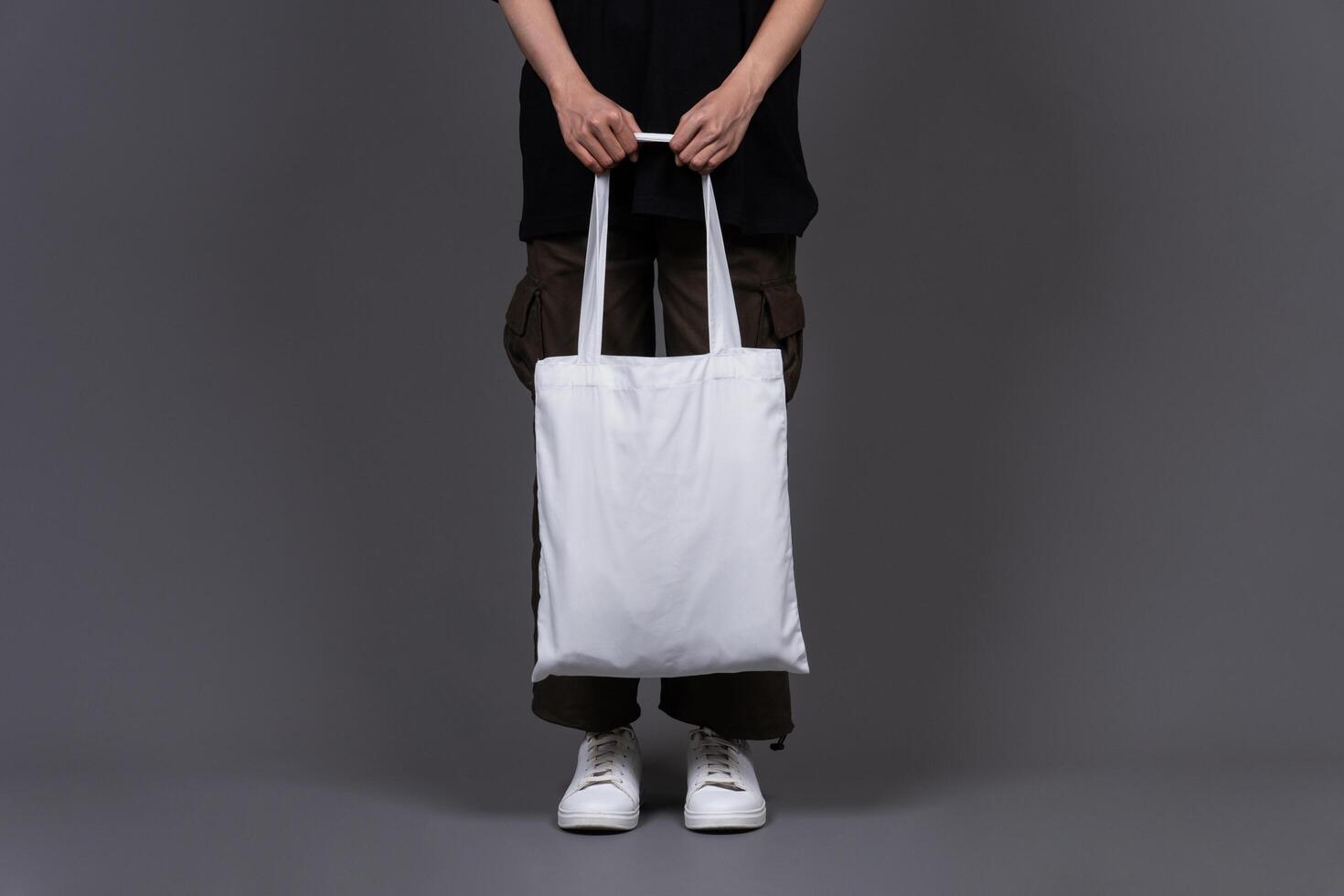 Front View of Woman Holding Blank Canvas Tote Bag, Eco-Friendly Reusable Fabric with Handle, Close-Up Mockup, No Plastic and Environmental Concept photo