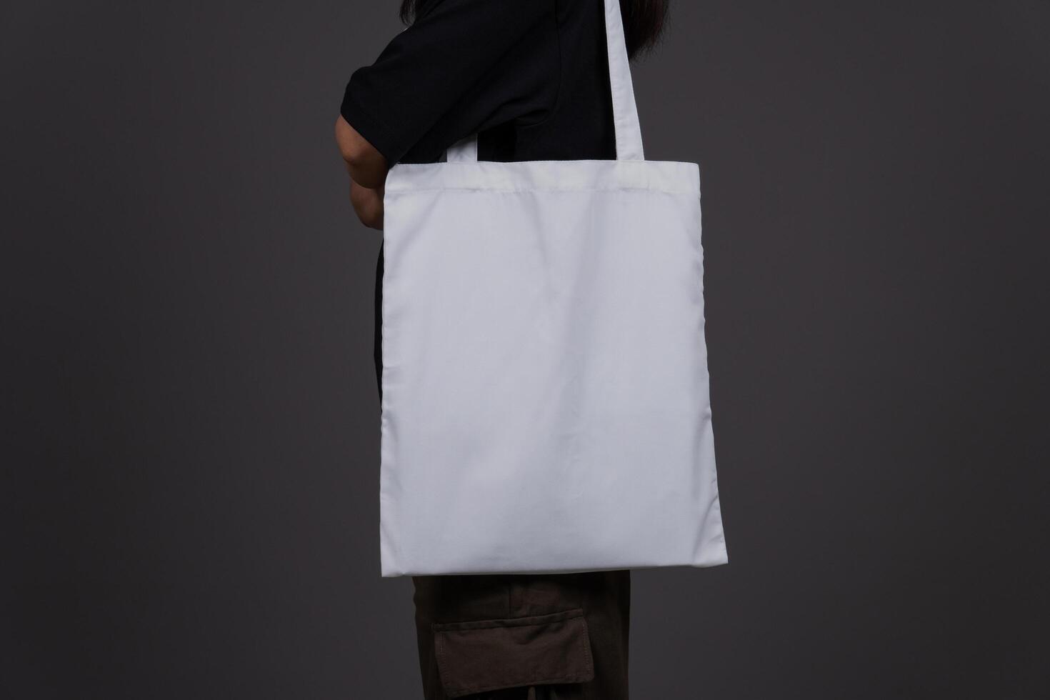 Side View of Woman Holding Blank Canvas Tote Bag, Eco-Friendly Reusable Fabric with Handle, Close-Up Mockup, No Plastic and Environmental Concept Isolated Background photo