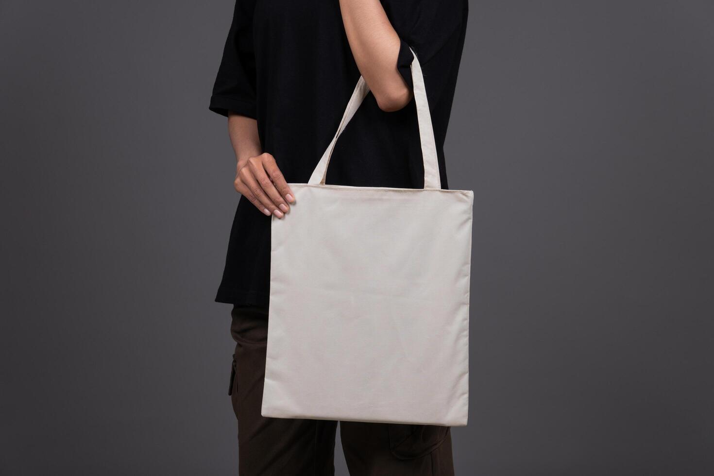 Front View of Female Holding Blank Canvas Tote Bag, Eco-Friendly Reusable Fabric with Handle, Close-Up Mockup, No Plastic and Environmental Concept photo