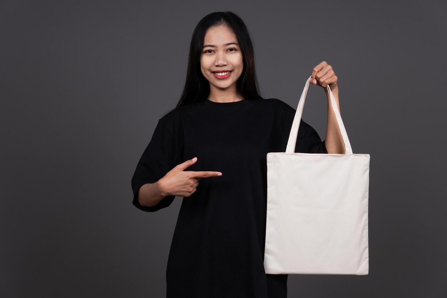 Front View of Woman Holding Blank Canvas Tote Bag, Eco-Friendly Reusable Fabric with Handle, Close-Up Mockup, No Plastic and Environmental Smiling Concept photo