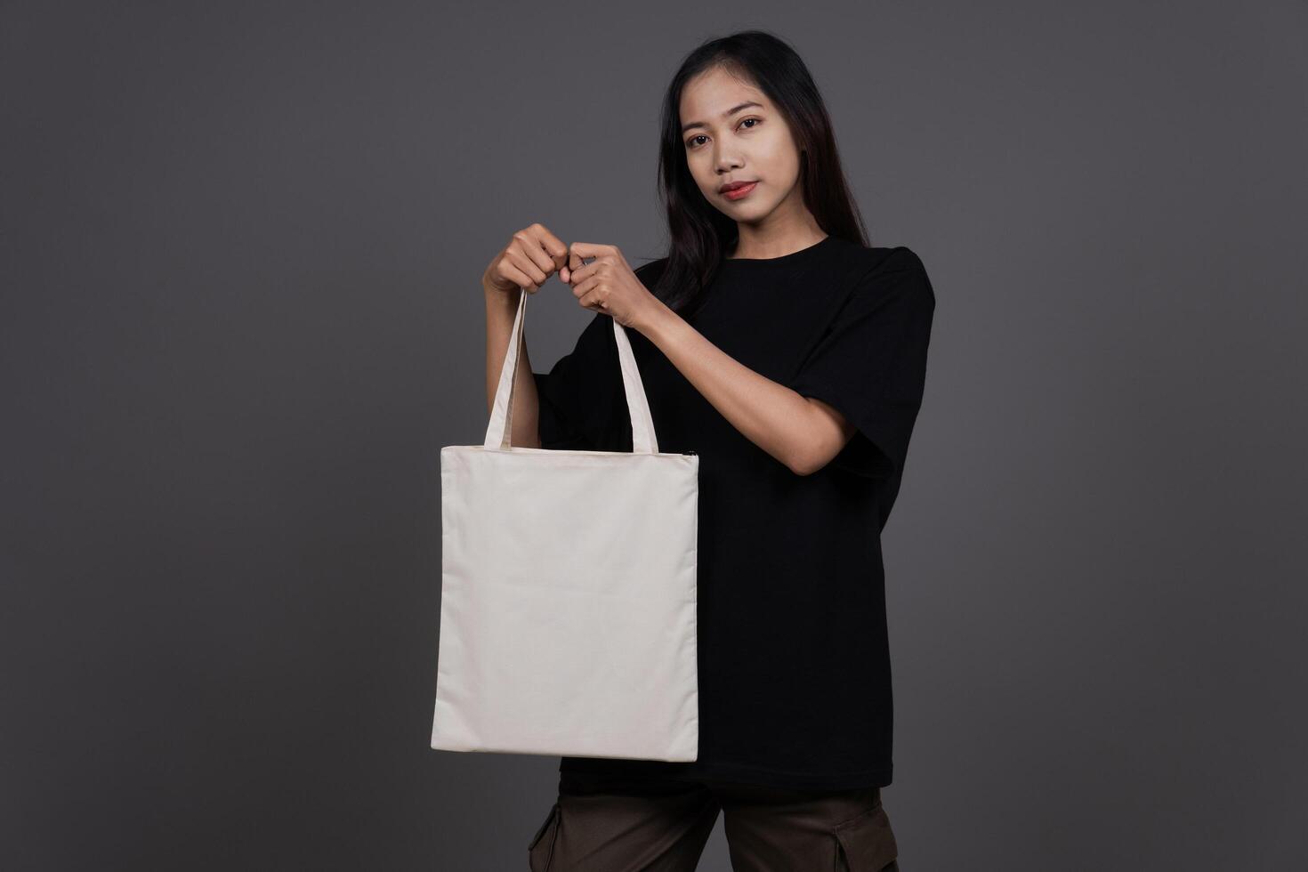 Front View of Woman Holding Blank Canvas Tote Bag, Eco-Friendly Reusable Fabric with Handle, Close-Up Mockup, No Plastic and Environmental Concept And Shopping photo