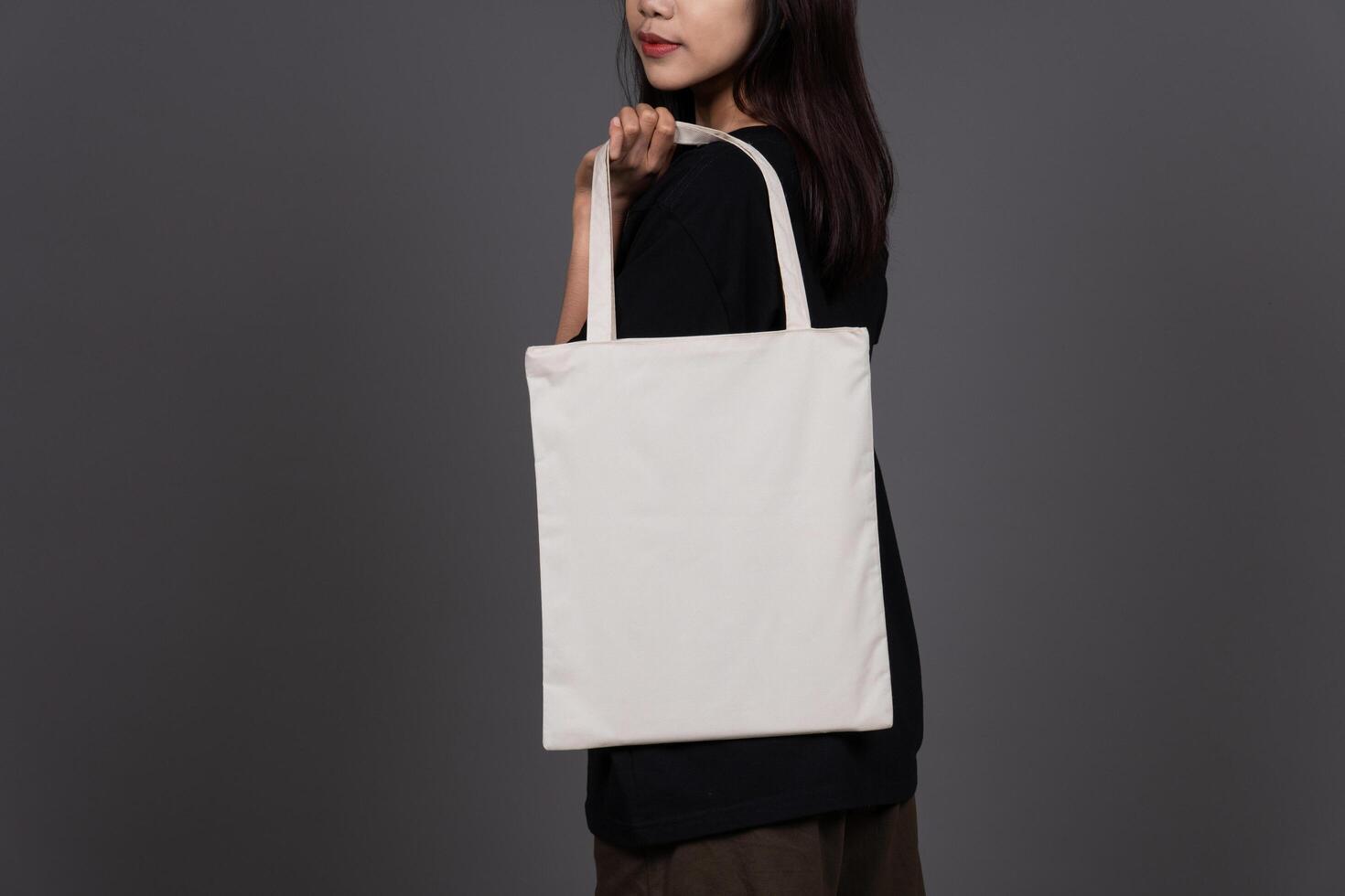 Back View of Female Holding Blank Canvas Tote Bag, Eco-Friendly Reusable Fabric with Handle, Close-Up Mockup, No Plastic and Environmental Concept photo