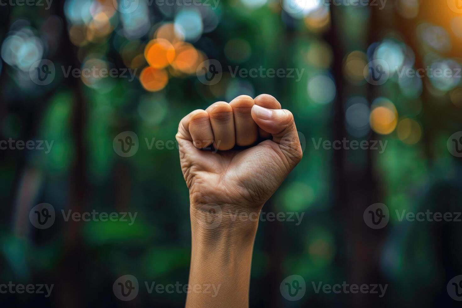 A fist is raised in the air in front of a forest photo