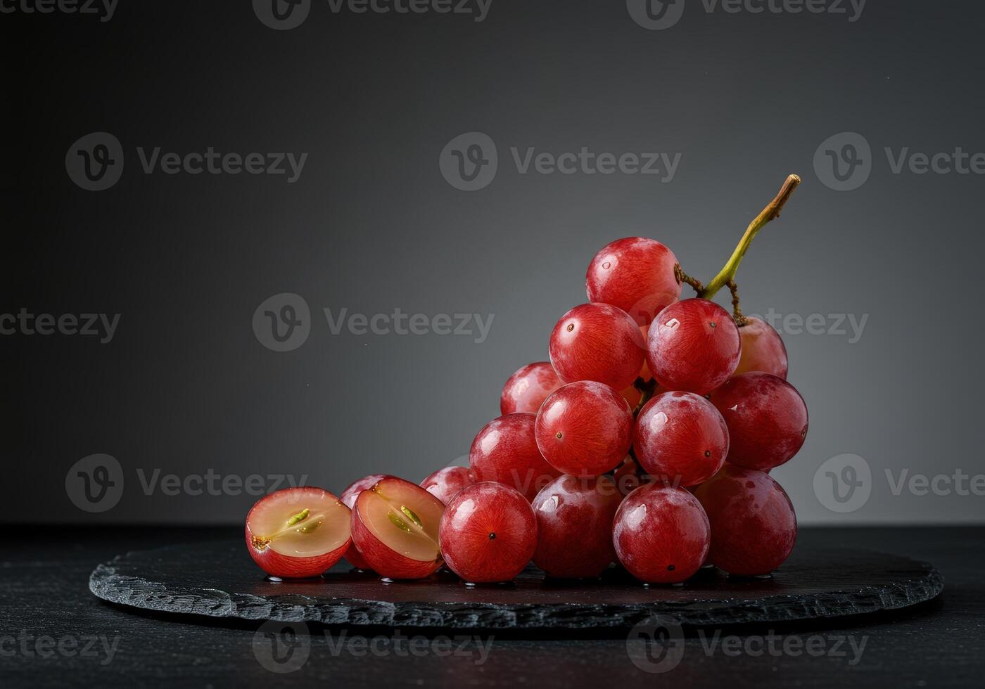 Fresh red grapes on a dark slate plate against a minimalist gray background photo