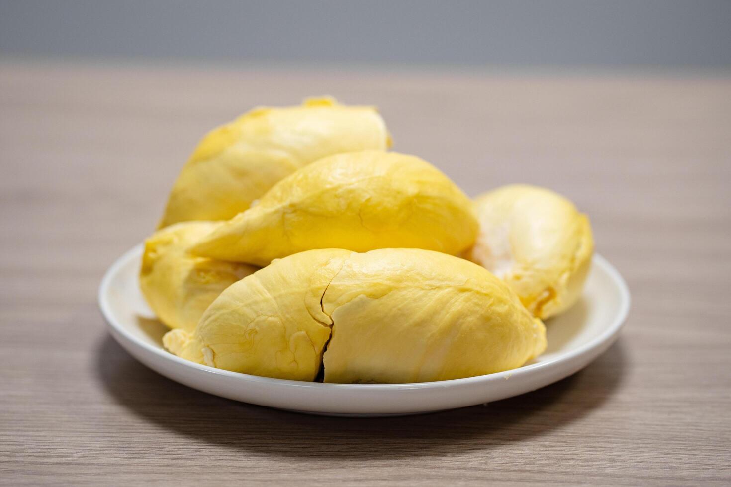 Fresh durian in white plate on wooden table with durian peel. Durian king of fruit. Tropical fruit. photo