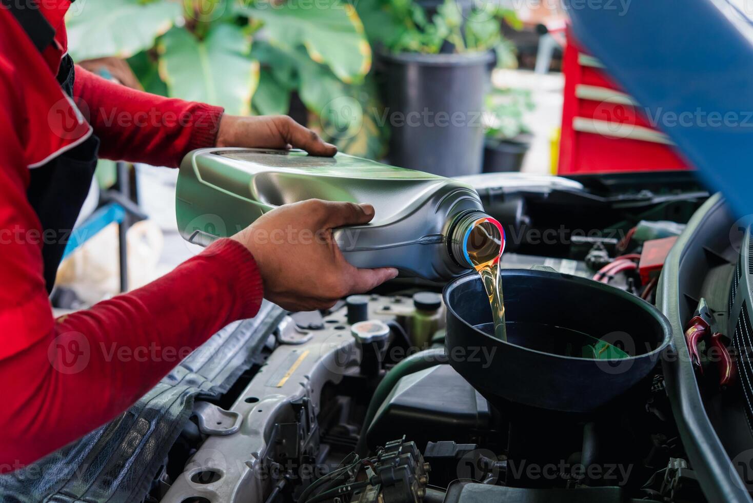 A man is pouring oil into a car engine photo