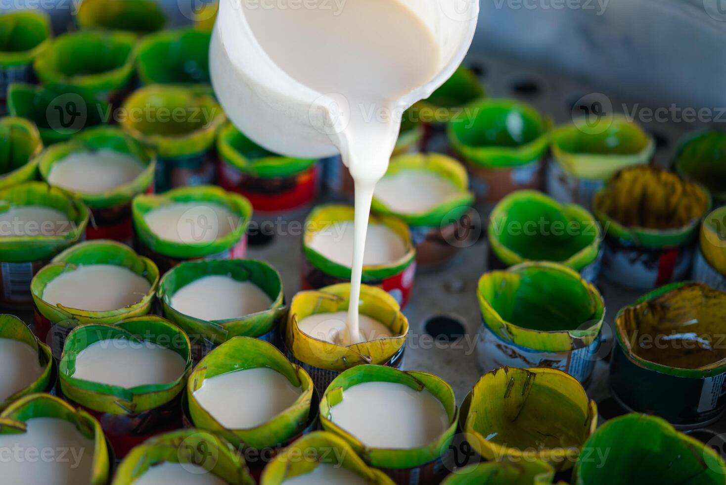 A person pouring milk into a container of green cups photo