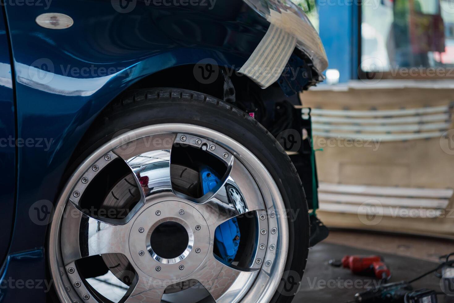 A blue car with a wheel and tire in the garage photo