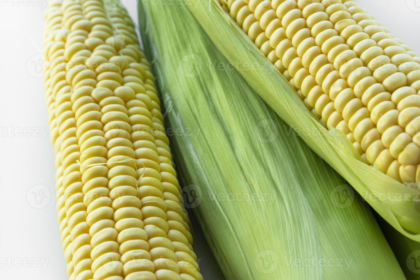 Close-up of fresh yellow corn on the cob with green husks. The vibrant kernels are perfectly aligned, natural texture and summer harvest freshness. Food, agriculture, organic. photo
