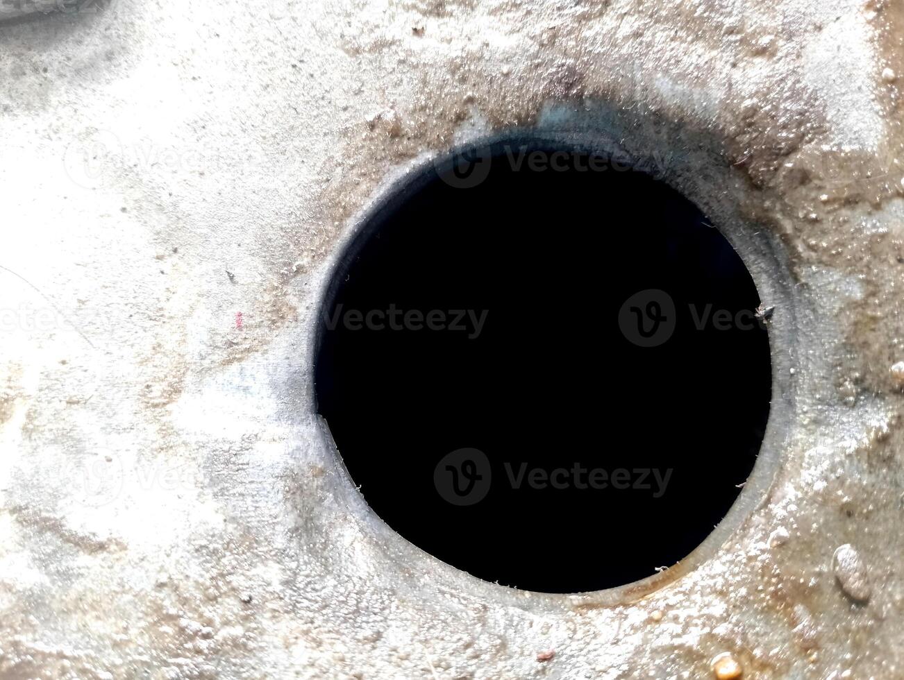 Close-up of a dark circular hole in a rough, textured surface. photo