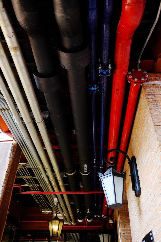 Detail of industrial pipes with ventilation systems and ducts conduits arrangement in mechanical system on ceiling of basement photo