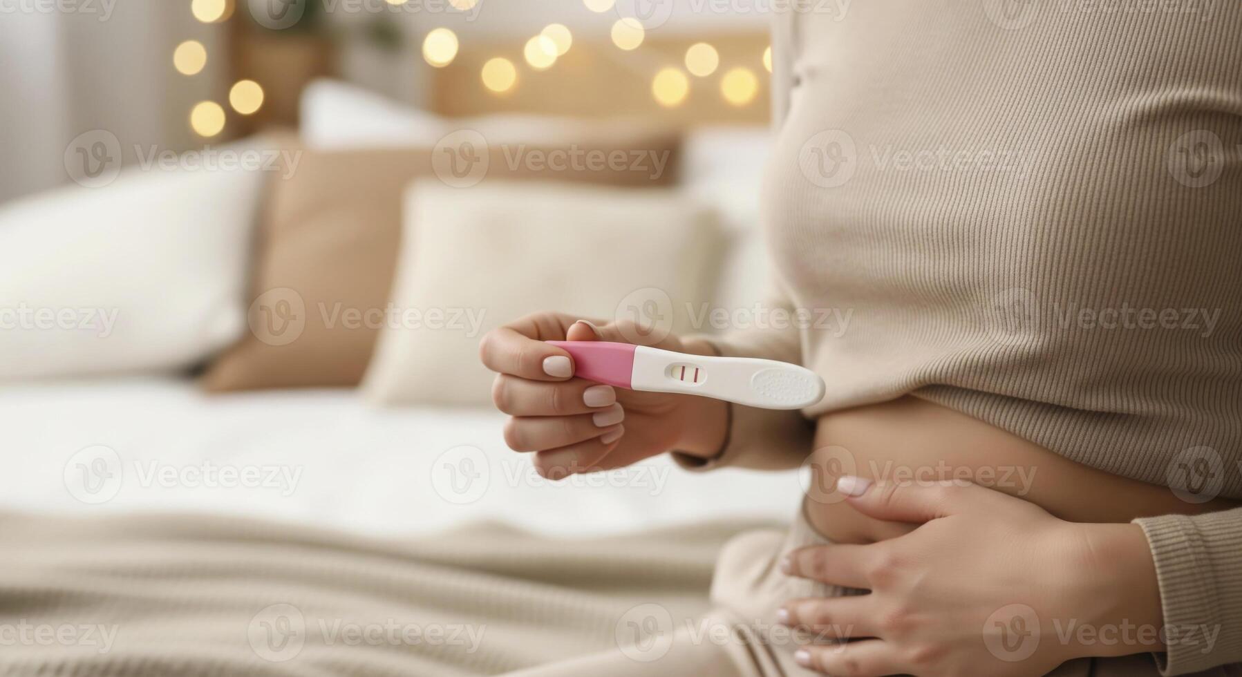 Woman's hand holds positive pregnancy test, gently touching flat stomach. Intimate moment of surprise and new life. photo