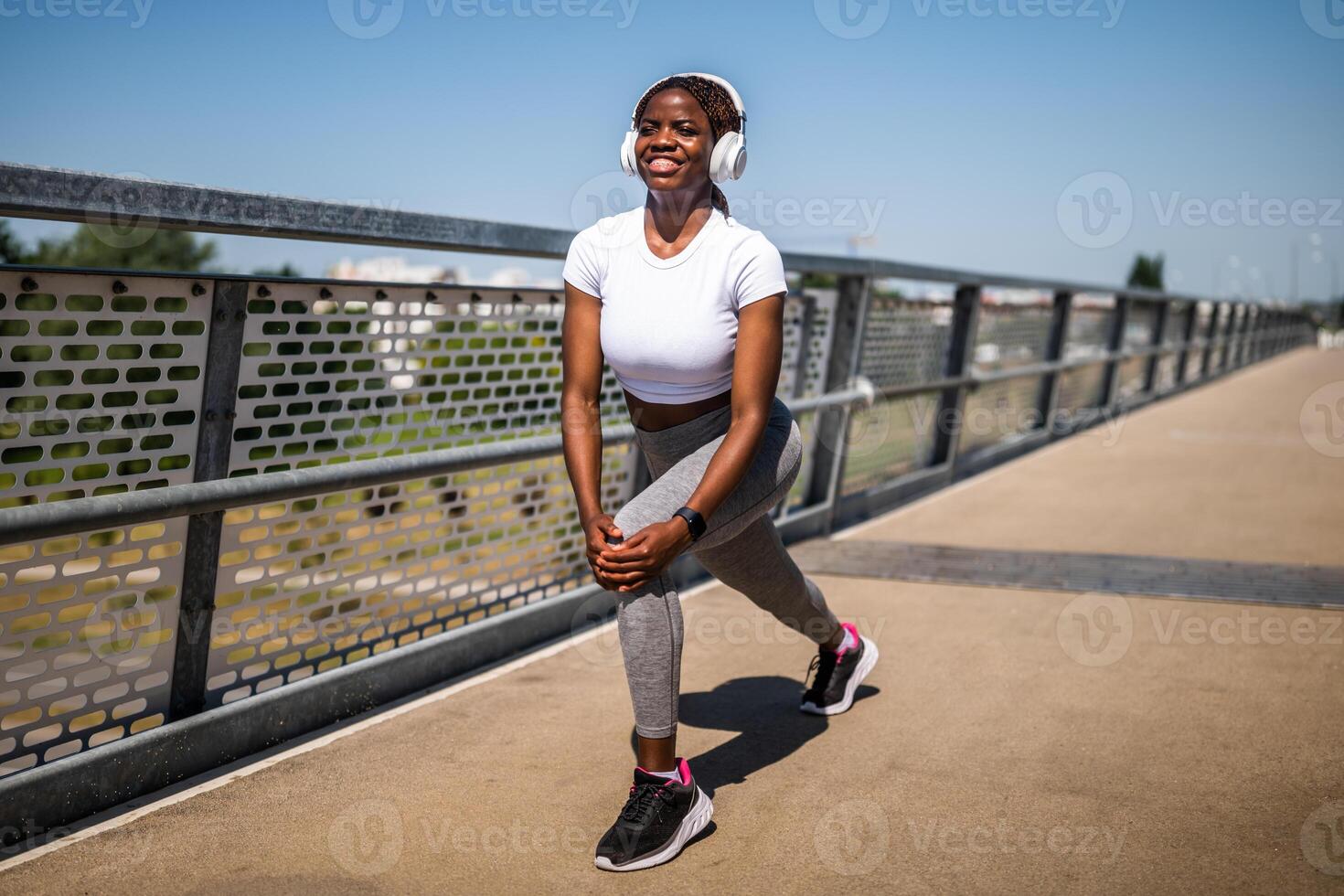 Focused African American female athlete stretching with effort and motivation before her daily physical activity outdoor. photo