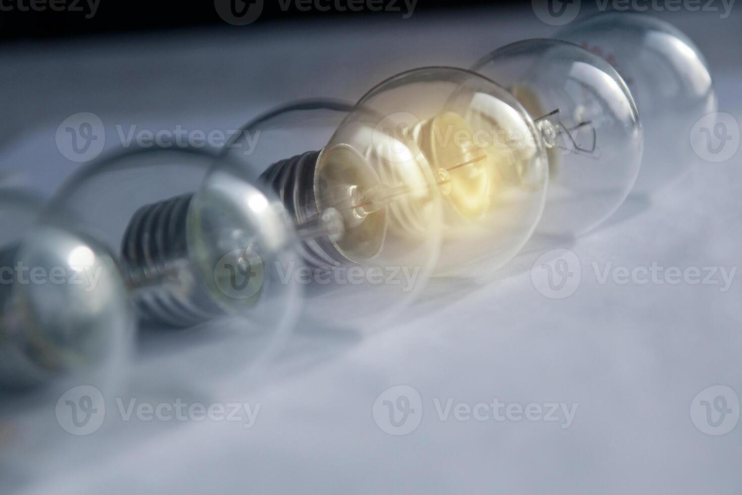 Idea concept. 6 small bulbs in row one is glowing. Selective focus. Toned blue. photo