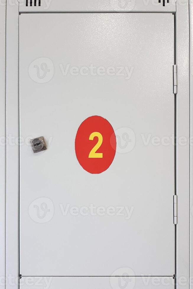 Metal gray box with lock and red sticker number 2. Box for visitor stuff at common store. photo
