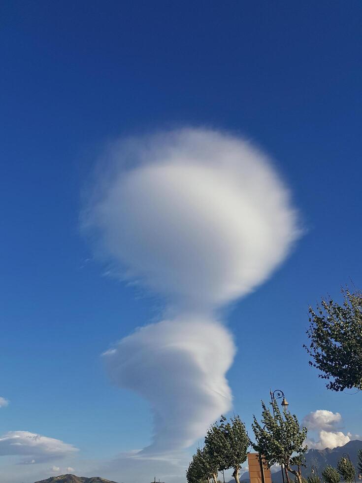 A natural cloud formation set against a clear blue sky highlights its striking shapes, creating a feeling of an impending storm. photo