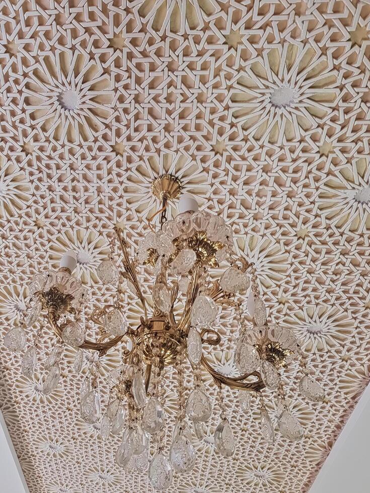 A breathtaking chandelier adorns the ceiling, boasting intricate patterns and geometric motifs, expertly crafted from gypsum to create a masterpiece that harmoniously fuses tradition and modernity. photo